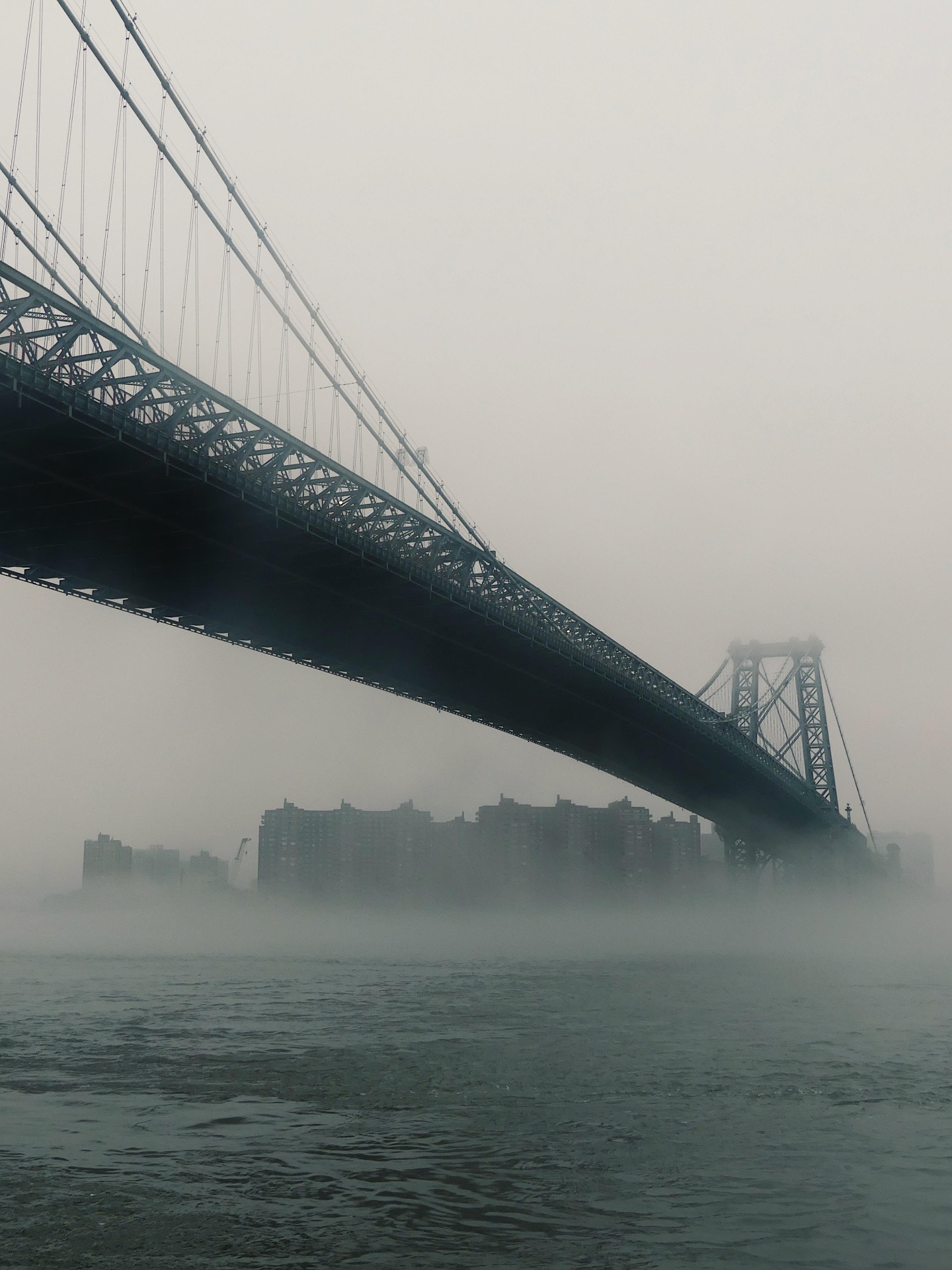 Williamsburg Bridge fading into mist over the East River.